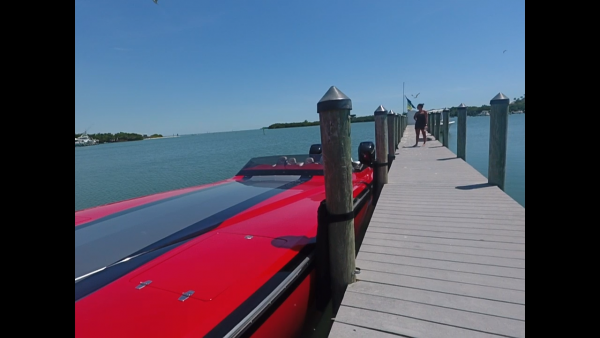 A red speed boat docked at a dock.