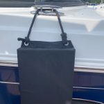 A black bag hanging on the side of a boat.